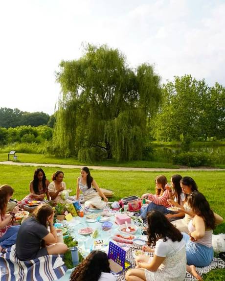 A circle of people sharing food on blankets